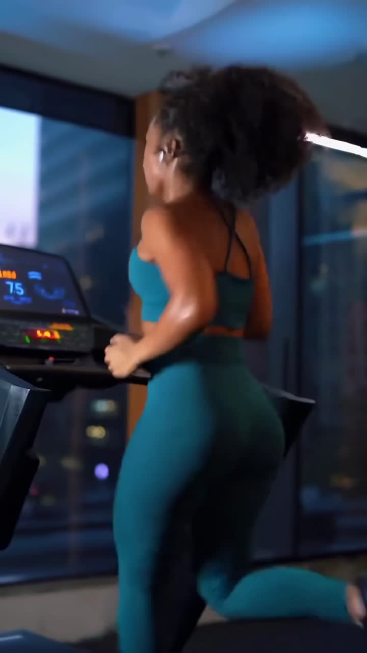 Video dinamico di una donna che corre sul tapis roulant, ripreso da una bassa angolazione posteriore in palestra