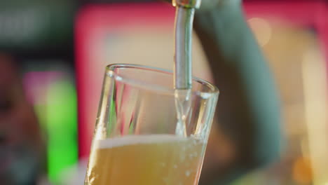 light beer poured into glass in pub closeup. black bartender fills mug with foamy lager from tap in bar. skilled barman works with drink in club