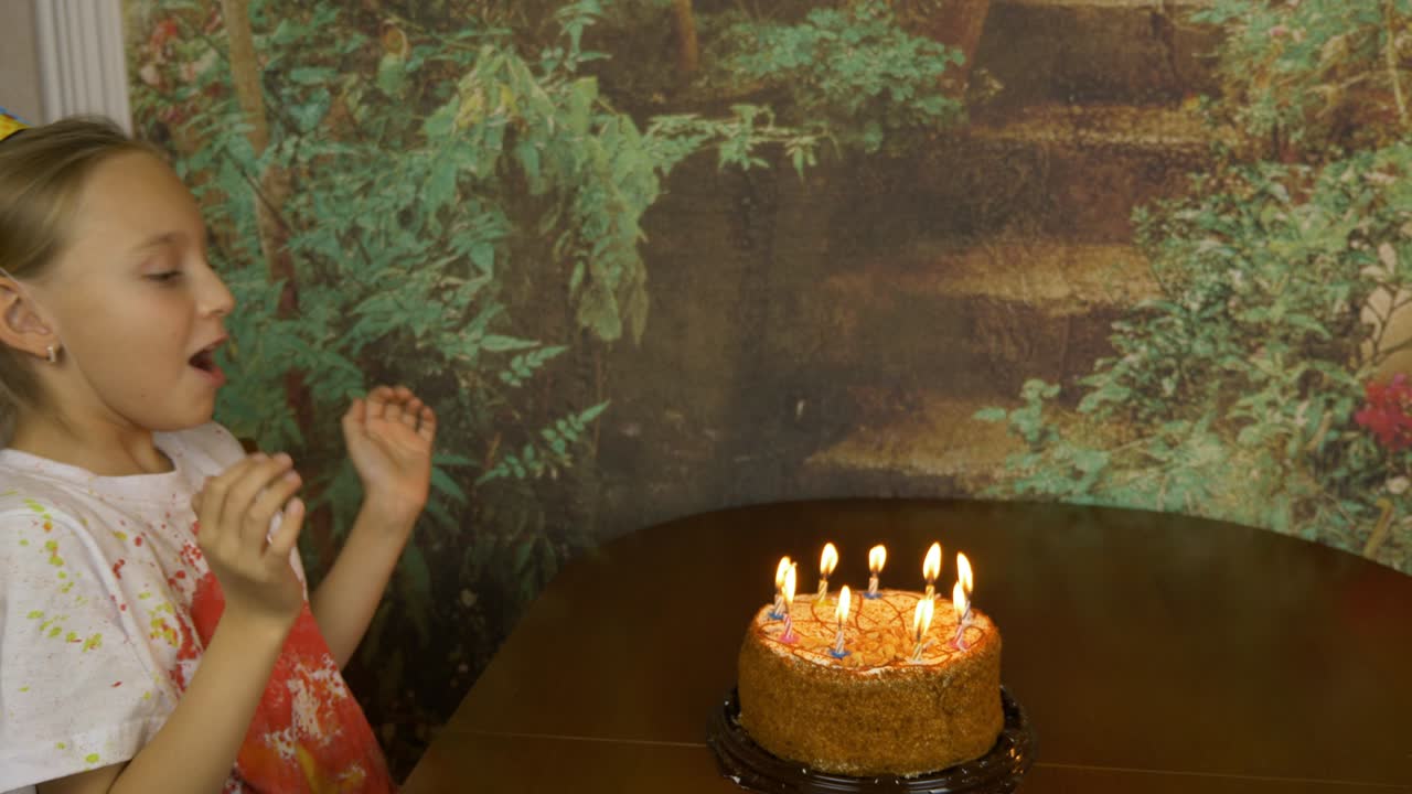 Funny girl can not blow birthday candles on cake. Joke party at home. Young girl blowing candles on cake. Lot of smoke and ash on table. Fast motion effect. Girl clapping.