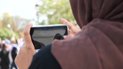 woman in hijab using smartphone outdoors