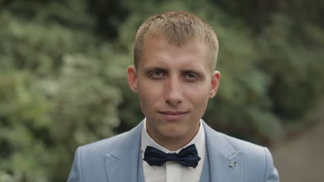 el novio en traje azul ajustando su corbata de papagaio