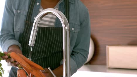 man with apron washing vegetables