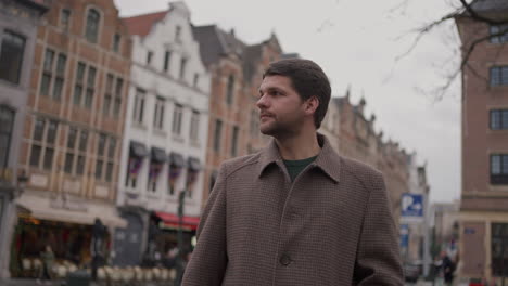 stylish hipster man in an overcoat looking around in brussels, belgium