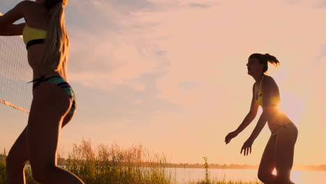 Primer-Plano-En-Cámara-Lenta-Y-Bajo-ángulo-Sun-Flare:-Chica-Atlética-Jugando-Voleibol-De-Playa-Salta-En-El-Aire-Y-Golpea-La-Pelota-Sobre-La-Red-En-Una-Hermosa-Tarde-De-Verano.-La-Mujer-Caucásica-Gana-Un-Punto.