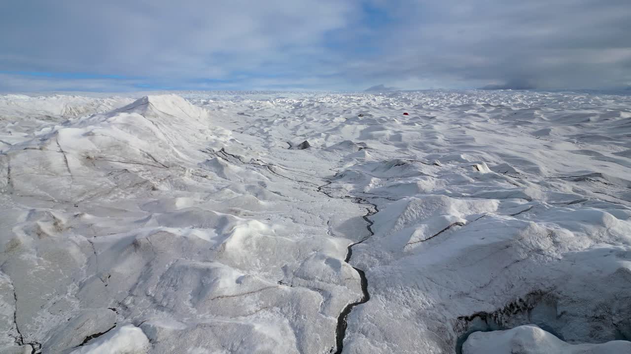Low flyover of frozen lake on barren, sunny arctic Greenland glacier