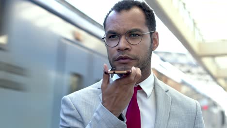 Serious-businessman-with-cell-phone-at-train-station