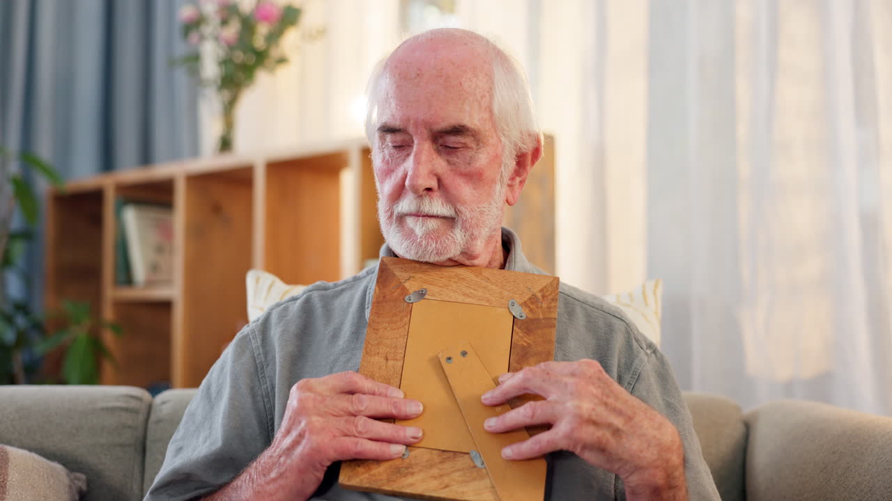 Elderly man looking at a photo frame at home