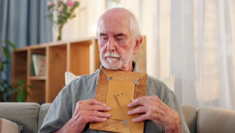 elderly man looking at a photo frame at home
