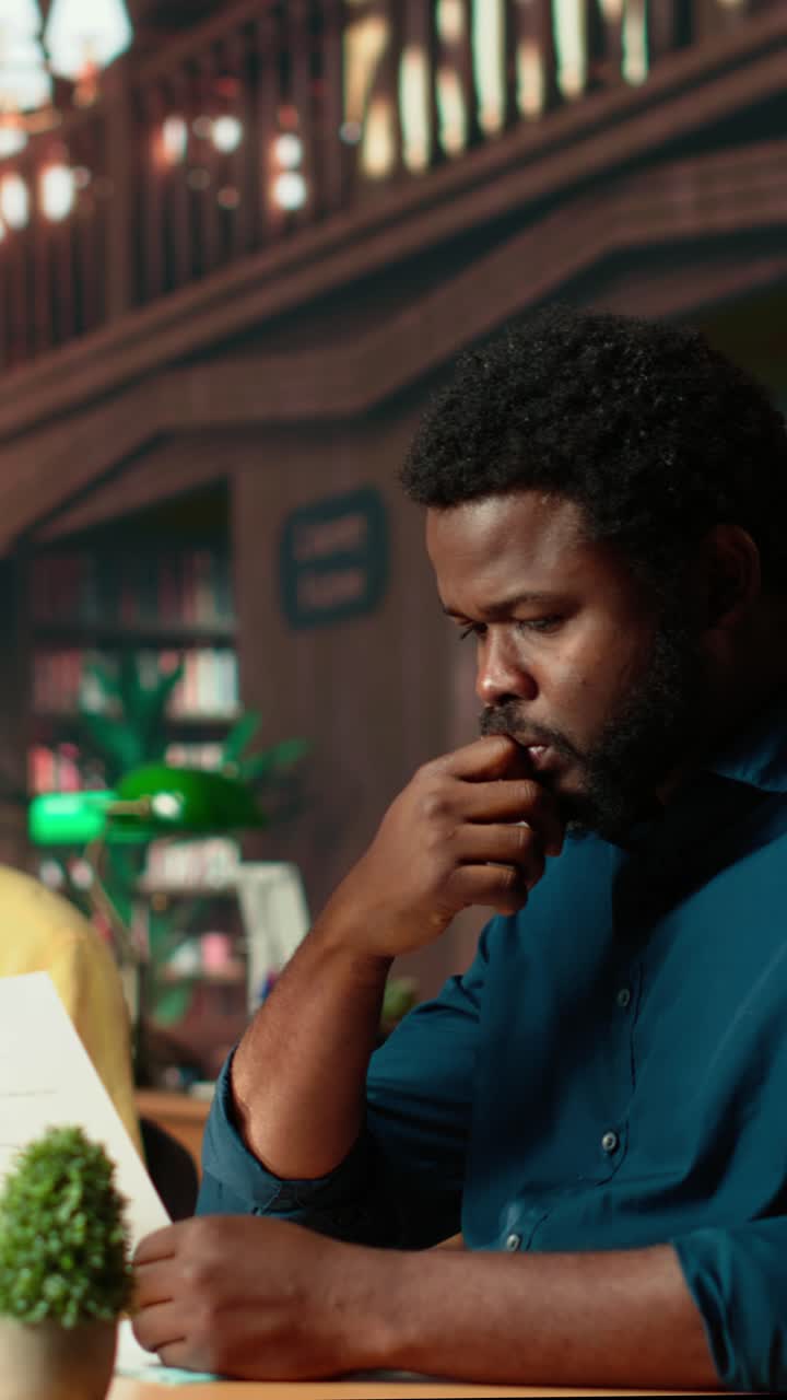African American Man Reading Document and Looking at Camera