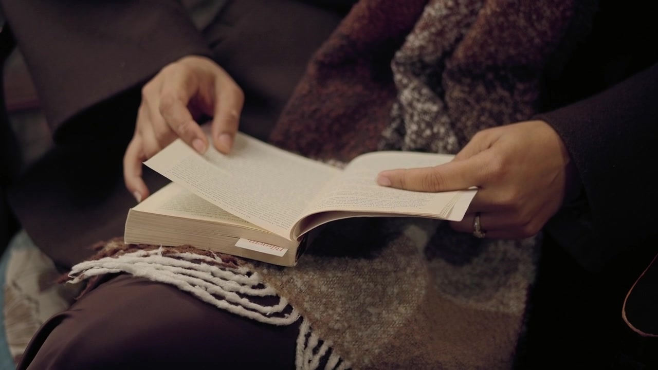 Mani di una persona che girano le pagine di un libro mentre legge