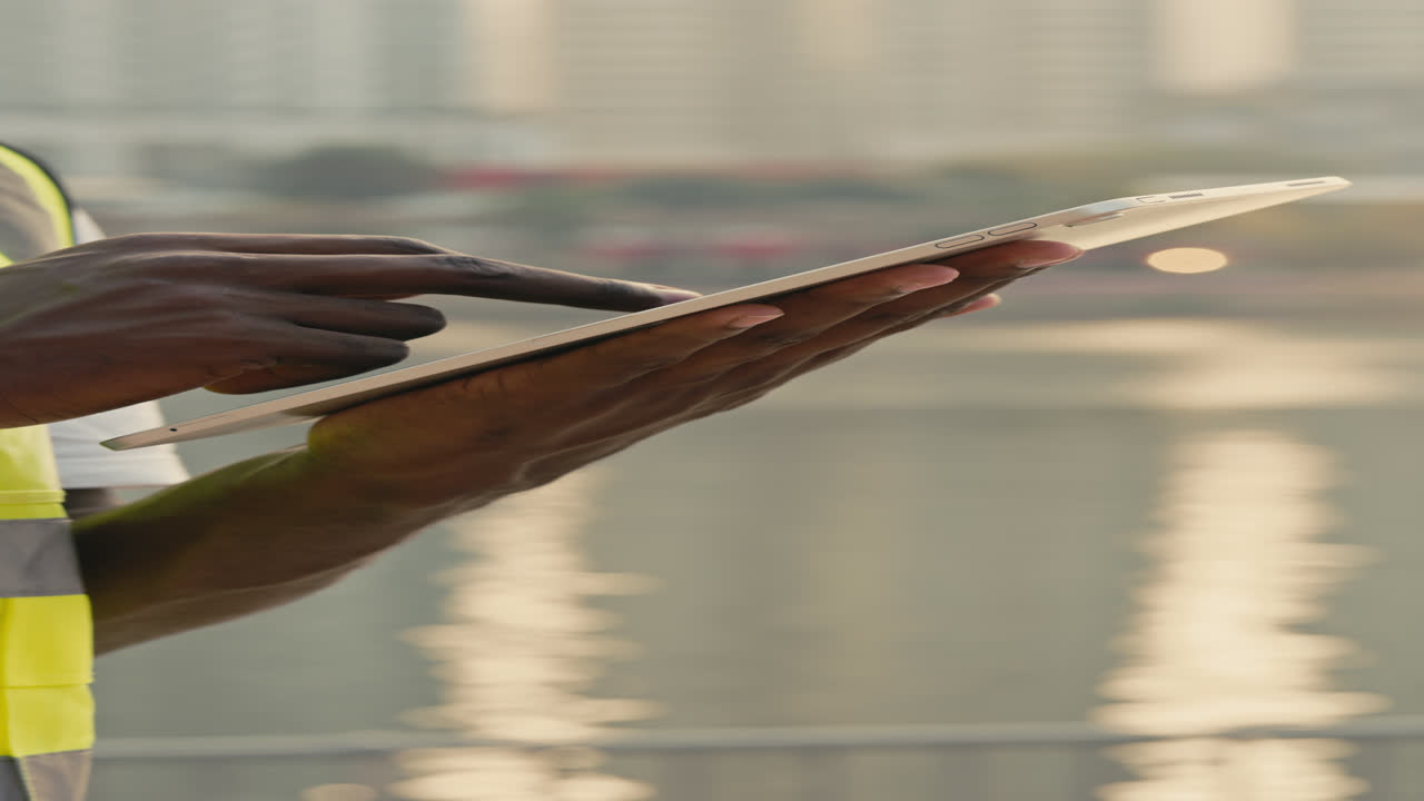 Construction worker using tablet outdoors by the water