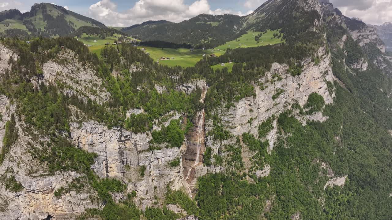 Swiss cliff waterfall drops through forested rock near Walensee lake