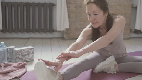 anciana estirándose y haciendo ejercicio en una alfombra de yoga en casa 1