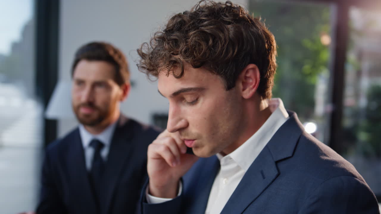 Disappointed businessman hearing bad news by smartphone standing office closeup