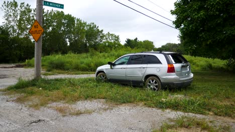 Stolen-car,-vandalized,-and-wrecked-left-abandoned-in-an-empty,-grassy-lot