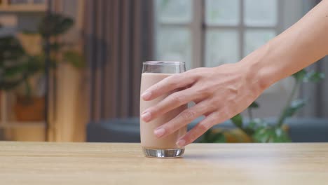 man hand take glass of chocolate milk on table