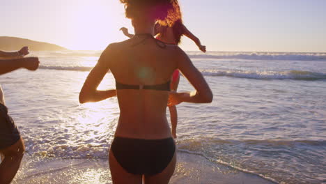 friends running into the ocean at sunset