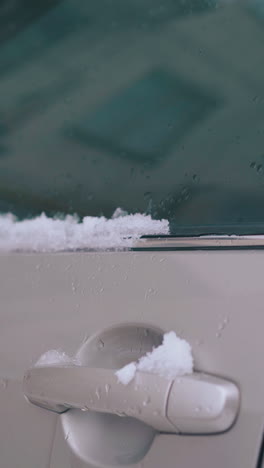 white snow lies on car with folded rearview mirror and front door on early spring day extreme close view