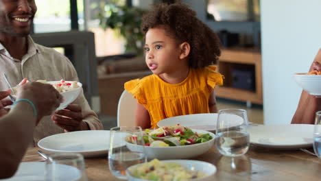 multi-generation family sitting around table serving food for meal at home