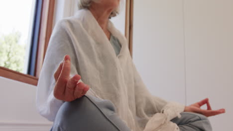 Senior woman meditating peacefully at home, practicing mindfulness and relaxation