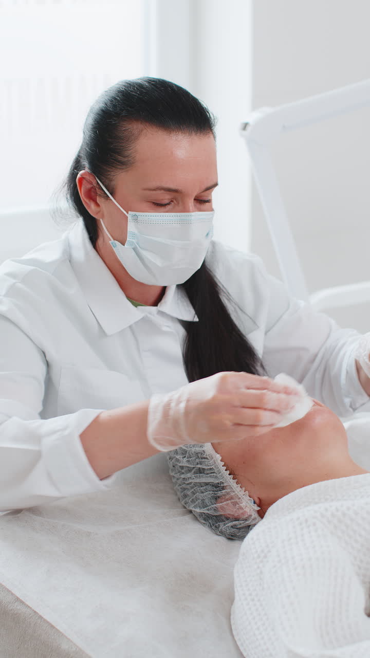 cosmetólogo médico limpia la cara y los ojos de la mujer procedimiento de limpieza con toallitas de algodón en la clínica de belleza