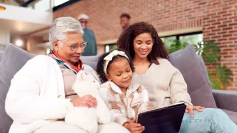 grandmother, daughter, and granddaughter enjoying family time with tablet