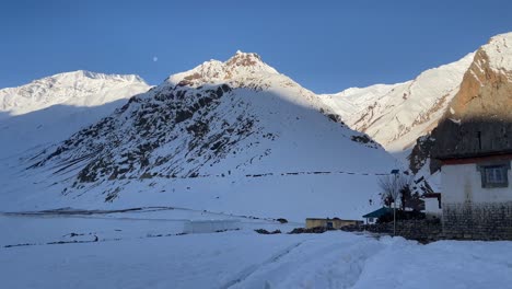 a small village with old stone house surrounded by snow on winter sunny day in himalayan mountains, spiti valley, himachal pradesh, india