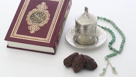 islamic holy book with rosary on a turnable white background, translation is quran kareem in arabic