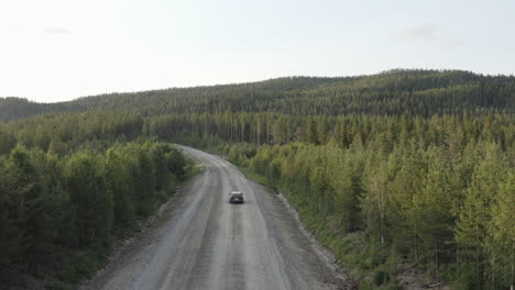 Vista-De-Dron-De-4-K-Sobre-Un-Coche-En-Un-Camino-Rural-De-Tierra-En-El-Bosque-En-La-Naturaleza