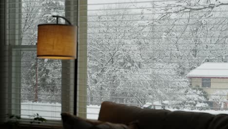 View-of-a-blizzard-happening-outside-of-a-home-with-a-lamp