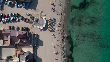 bird eye view looking down of a beach with many umbrellas and blue crystal sea water - in cabo de palos, murcia region - summer time in spain