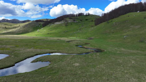 flight over a winding mountain stream with clear water on a sunny spring day