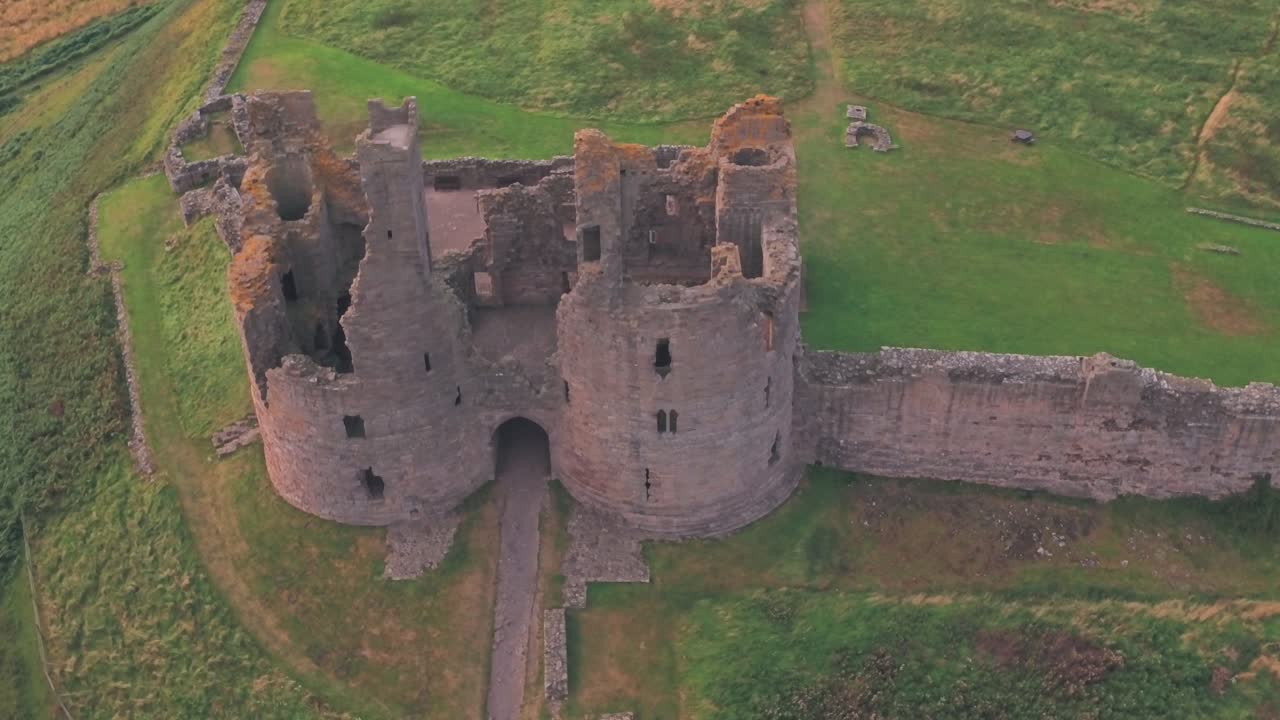 Dunstanburgh Castle at sunset in Northumberland, England, UK. Aerial drone view