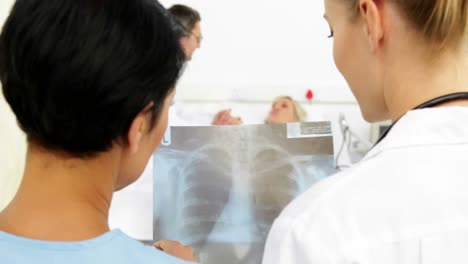 doctors studying xray in front of sick patient in bed