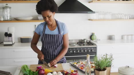 happy african american woman preparing dinner in kitchen