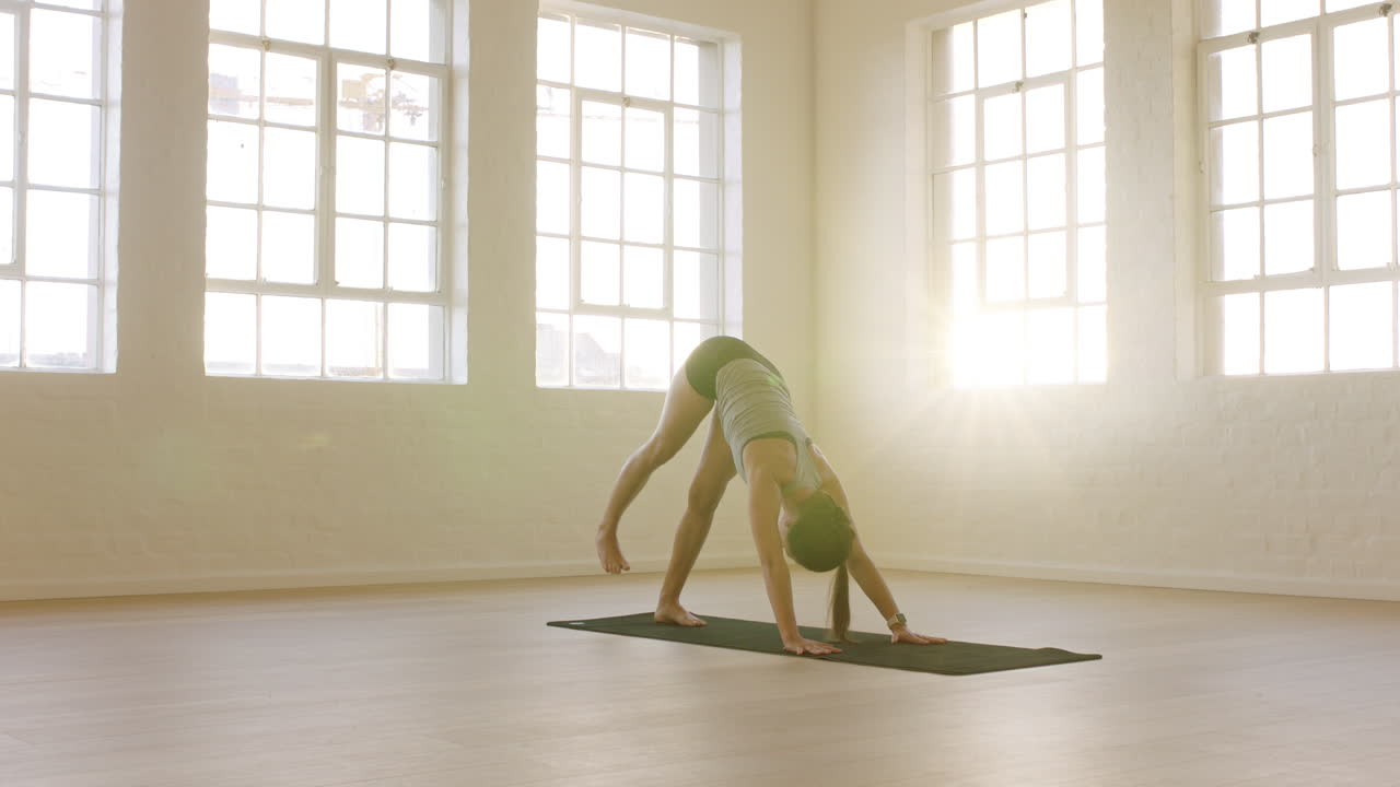mujer de yoga saludable practicando pose de perro boca abajo de tres patas disfrutando de un estilo de vida físico haciendo ejercicio en un estudio de entrenamiento que estira el entrenamiento en una colchoneta de ejercicios al amanecer