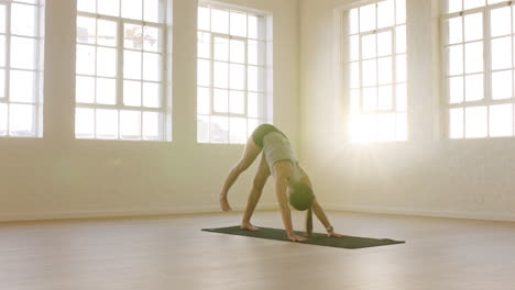 healthy yoga woman practicing three legged downward facing dog pose enjoying fitness lifestyle exercising in workout studio stretching training on exercise mat at sunrise