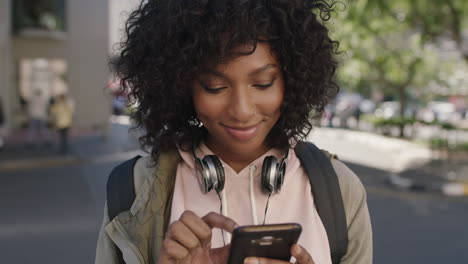 Retrato-De-Una-Joven-Y-Atractiva-Mujer-Afroamericana-Enviando-Mensajes-De-Texto-Navegando-Usando-Un-Teléfono-Inteligente-Viajes-Urbanos-Relajados-E-Informales