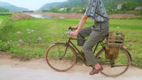 view of a farmer paddling his bicycle on a cloudy day surrounded by rice fields on a hilly terrain in lang son city, vietnam