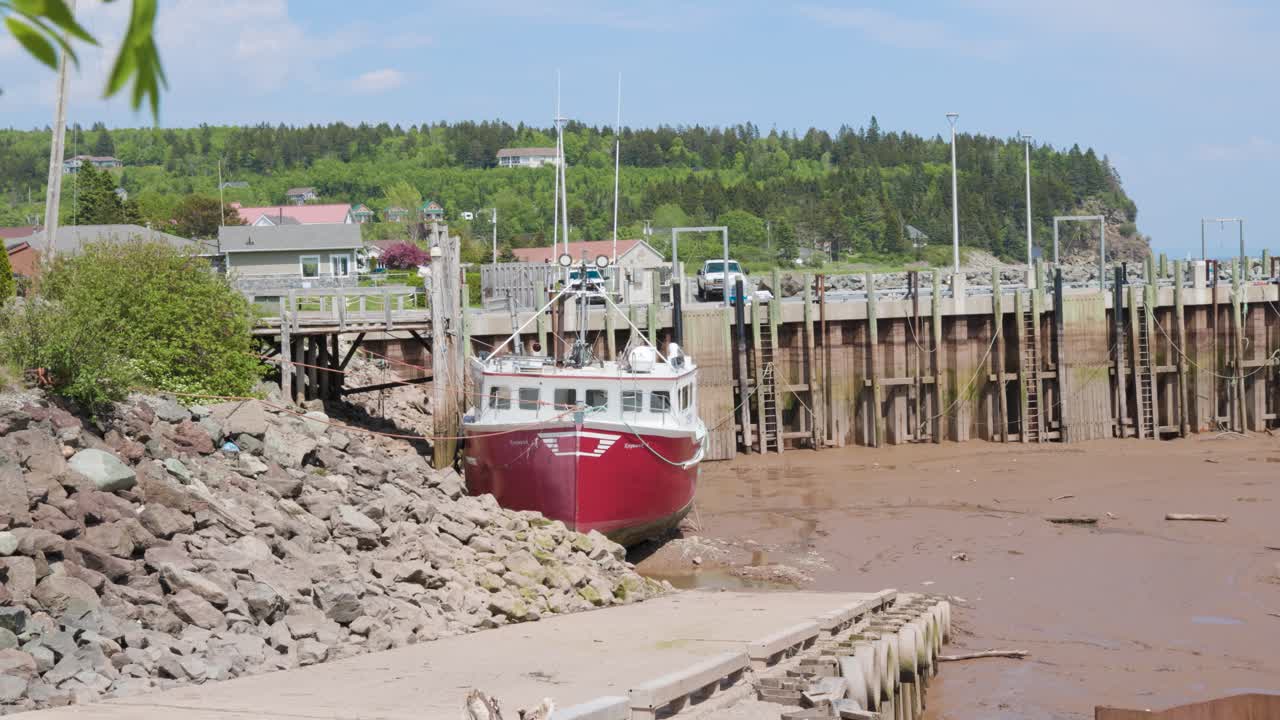 Slow motion shot of a commercial fishing boat that is beached during low tide at a small pier located in a small village in the Bay of Fundy, New Brunswick, Canada shot in 4k