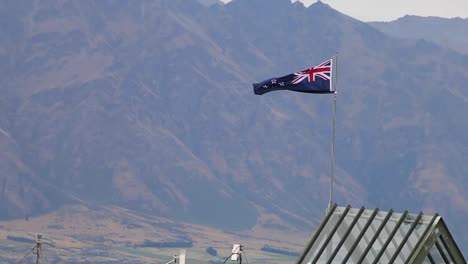 flying the new zealand flag on top of a mountain