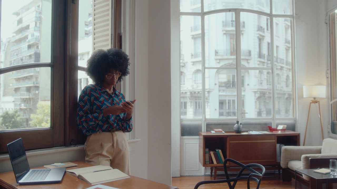 Giovane donna d'affari di colore che usa lo smartphone in ufficio.