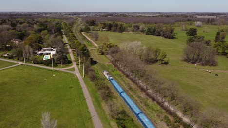 blue train crossing green countryside of buenos aires, argentine