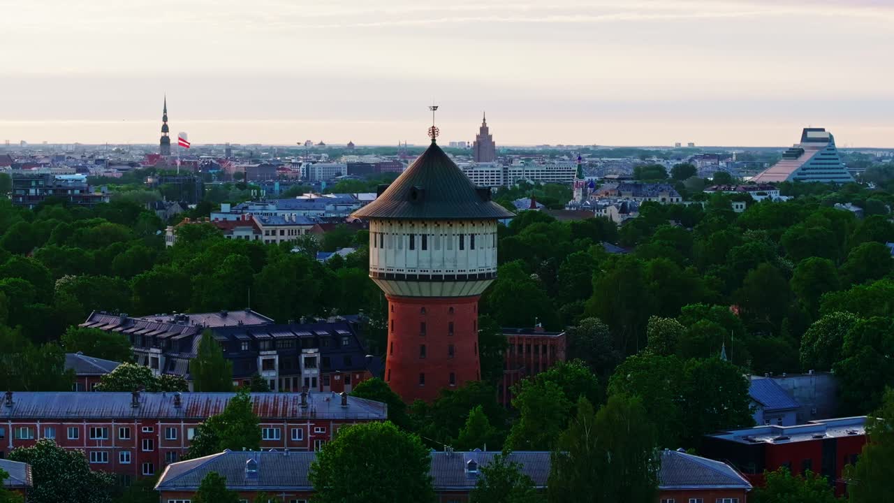 Panorama över Rigas stadssiluett vid soluppgången, lugna flodreflektioner och moderna torn.