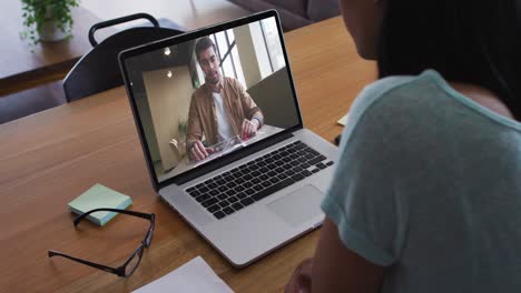 mid section of african american woman having a video call with male colleague on laptop