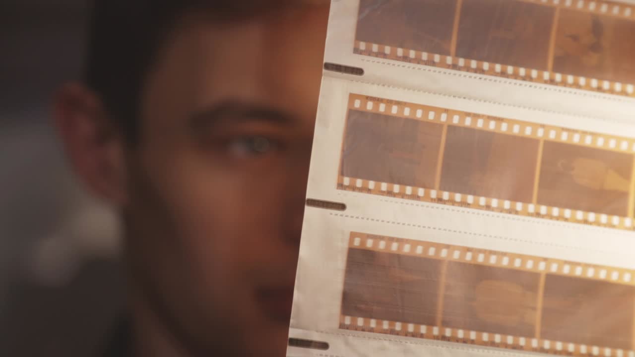 오래된 빈티지 필름 네거티브 스트립을 보는 남자