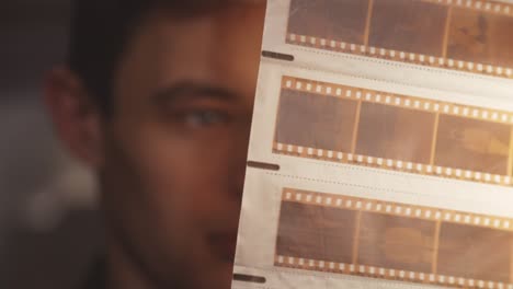 man looking at old vintage film negative strips