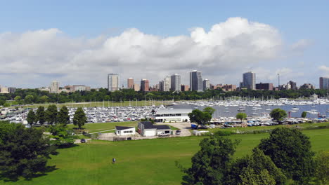 wide pull away aerial view of sailboats in a quiet bay with city skyline in the background