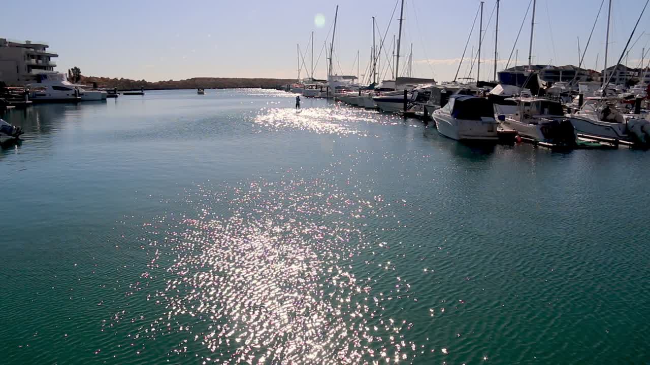 On beautiful Summer&rsquo;s day a Paddle boarder rows on water in a marina