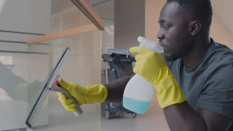 close up view of cleaning man wearing gloves cleaning stair railing and crystals inside an office building